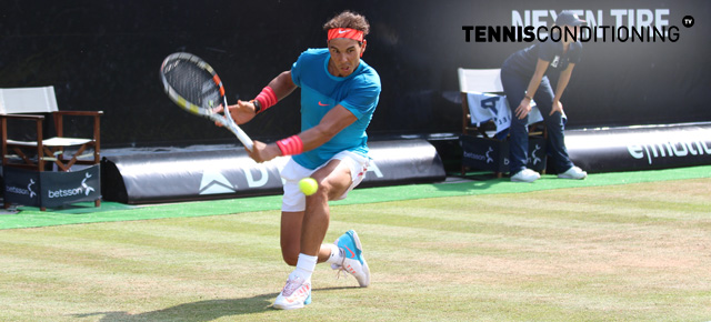 Rafael Nadal playing tennis on a grass court.